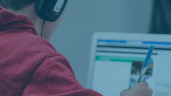  En person studerar på en dator med hörlurar på. 
